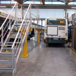 Adjustable catwalk platform with stairs used for bus maintenance.