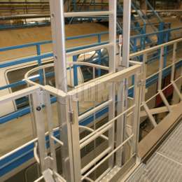 Ausfahrbare, gegengewichtete Leitern für den sicheren Zugang zu Arbeitsbühnen in einer Zugwerkstatt.