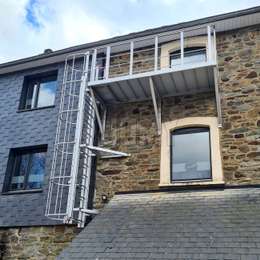 Maßangefertigter Balkon, der mit einer herabgleitenden Leiter an einer alten Fassadenwand verwendet wird, um aus dem Fenster eines Hauses zu entfliehen.