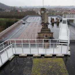 Fire escape walkway put a on a flat roof with ballast and leading to an evacuation staircase.