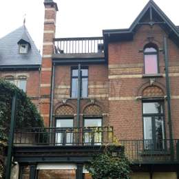 Closed black fire escape retractable ladder on historical brick facade.