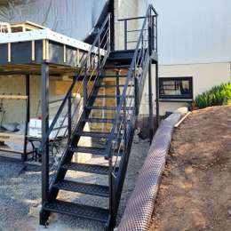 Black outside stairs with landing and support columns to access a roof terrace