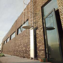 Cage ladder with guard door for accessing a flat roof.