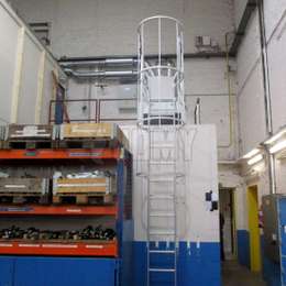Échelle fixe à crinoline utilisée pour accéder une mezzanine dans un entrepôt.