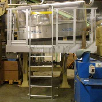 Echelle permanente, utilisée pour accéder à une station de travail avec machine, sur une ligne de production dans une usine de tabac.