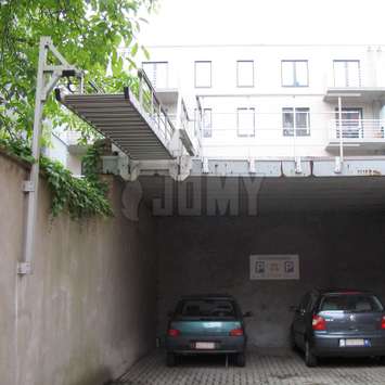 Escalera levadiza utilizada como escalera de incendios desde un edificio de apartamentos hasta un estacionamiento.