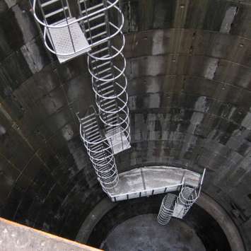 Escalera con jaula de seguridad con plataformas de descanso utilizadas en un embalse/pozo industrial.