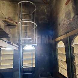 Escalera con acceso lateral y jaula para subir a una plataforma en el campanario de una iglesia 