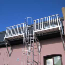 Escalera de incendios con jaula y balcones de acceso para una ventana velux en un partamento en un ático.