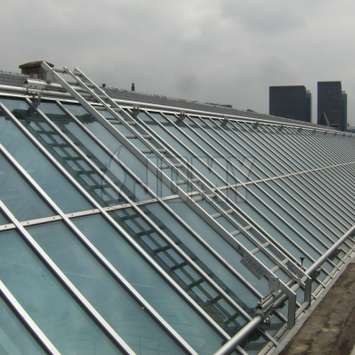 Escalera de mano inclinada sobre/bajo rieles para la limpieza de ventanales en el tejado - Unidad de mantenimiento de edificios