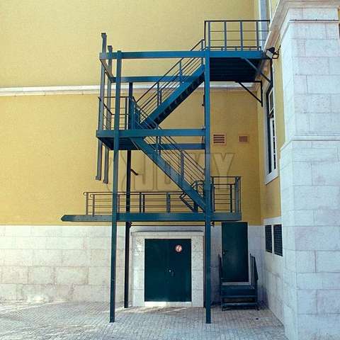 Escaleras negras de evacuación instaladas en un callejón peatonal en la parte trasera de un edificio.