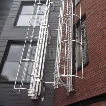 Escalera extensible perpendicular a la pared con jaula de seguridad, para evacuación de incendios.