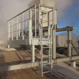 Escalera fija y plataforma de trabajo para acceso a máquinas Escalera con extensiones superiores ensanchadas usadas para subir a una plataforma de trabajo industrial necesaria para el mantenimiento de máquinas en el techo.