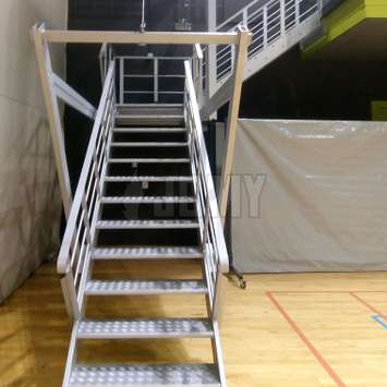 Escalera retráctil con sistema de cables y poleas en un gimnasio.