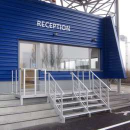 Escalera y plataforma de aluminio para acceder a la recepción de un edificio público.