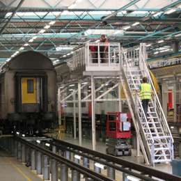 Escalera industrial y plataforma para acceder a alturas en la industria del transporte ferroviario.
