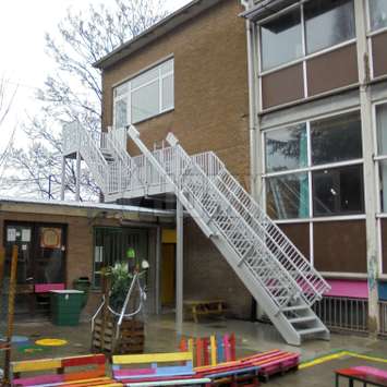 Notausgangstreppe mit versenkbarem Lauf in einem Schulhof.