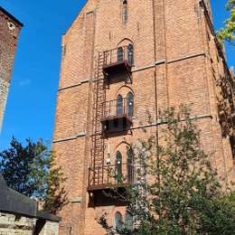 Fire escape cage ladder and access balconies for window egress on a historical brick building.