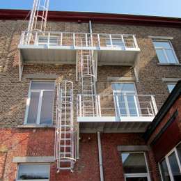 Fire escape solution for multiple windows and comprising of balconies, cage ladders and a drop-down ladder for the evacuation of an apartment building.