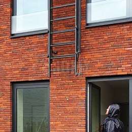 Window fire escape drop-down ladder attached to a brick wall.