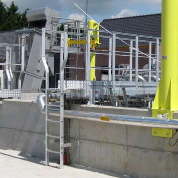 Fixed permanent ladder used for height access to a walkway in an outdoor facility.