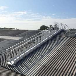 Inclined walkway with guardrails used on a factory roof.