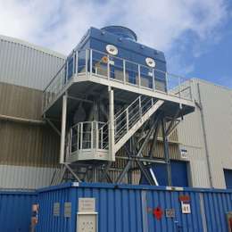Catwalk platform with stairs on tower structure for industrial machine maintenance.