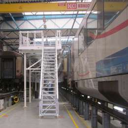 Access platform and stairs for working on train cabin tops in a workshop.