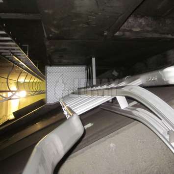 Lifeline curved rail on top of an access ladder for safe parapet crossing.