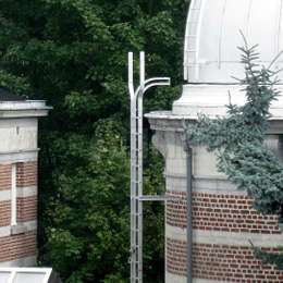 Ladder with top lifeline extension for roof access on a tower.