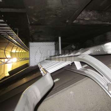 Riel curvo de la línea de vida en la parte superior de una escalera de acceso para el cruce seguro de barandas.