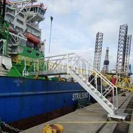 Mobile stairs and platform used to access a docked boat in a shipping port.