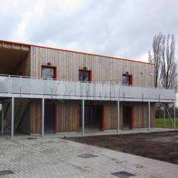 Passerelle fixée au mur et reposant sur des poteaux de soutien; utilisée pour l'accès au bâtiment le long de la façade.