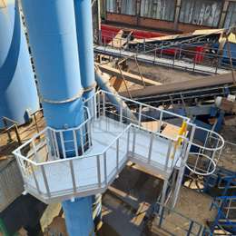 Plataforma de trabajo con escalera jaula de acceso sobre chimenea trituradora para medidas periódicas de emisiones.