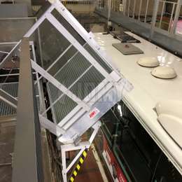 Plateforme baculante en aluminium pour atteindre les toits de bus dans un atelier.