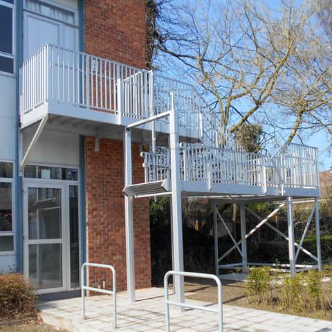 Fire evacuation stair with an anti-burglar retractable flight installed in a school courtyard.
