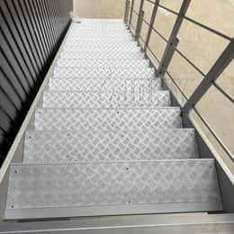 Extruded step profile with anti-slip tread plates with five-bar pattern.